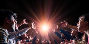 People reaching out towards a growing bright light.