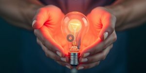 Person examining a lightbulb with gears.